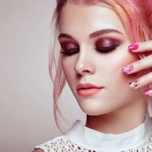 A woman with pink hair and purple eye shadow.