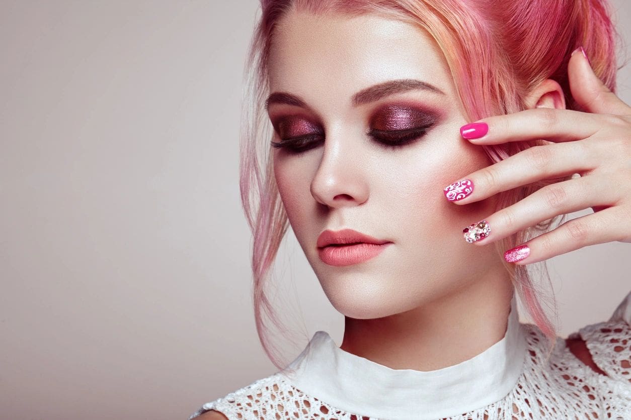 A woman with pink hair and purple eye shadow.