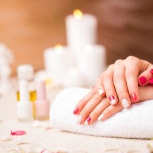 A woman with red nails is getting her hands painted