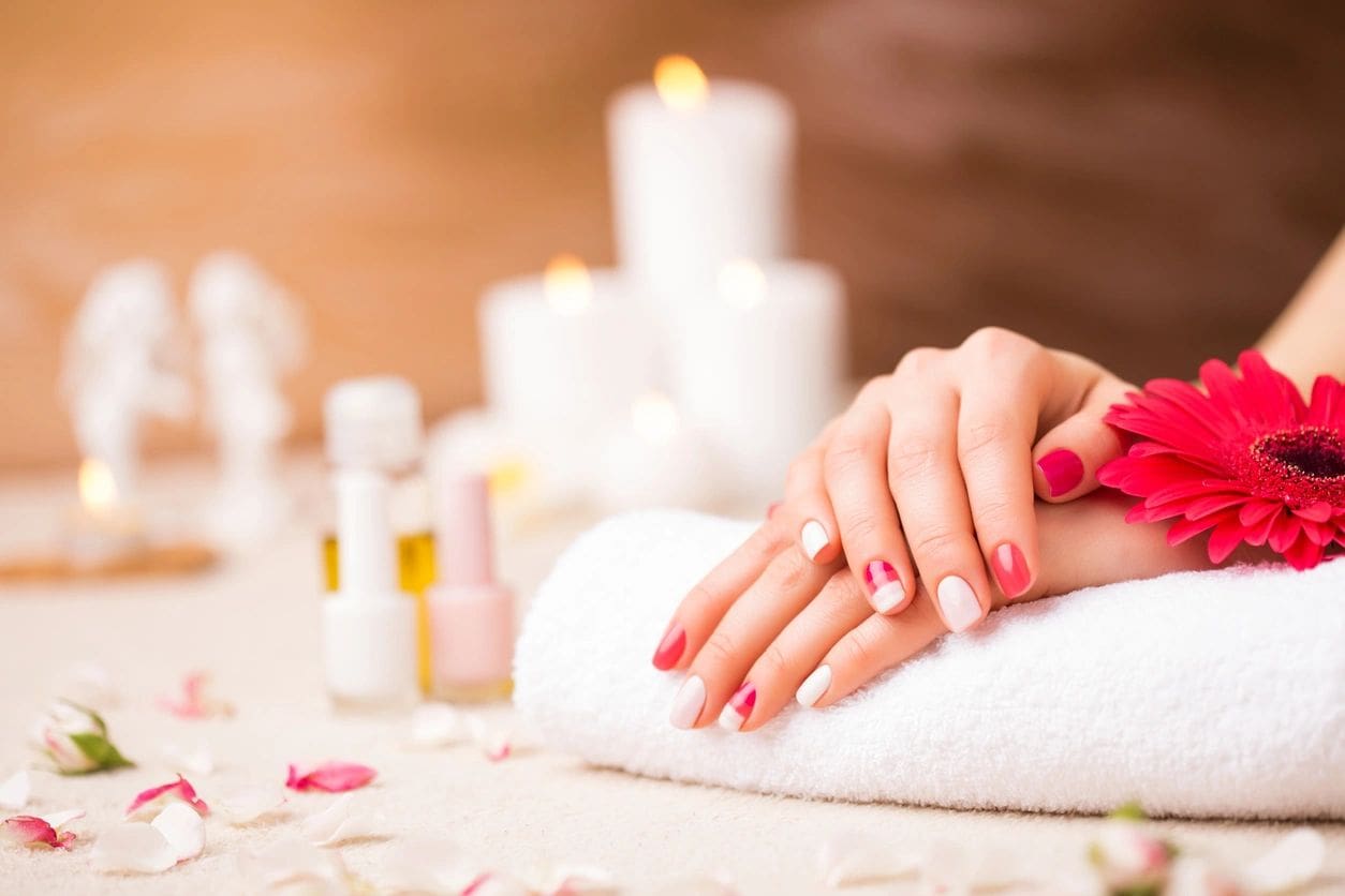 A woman with red nails is getting her hands painted