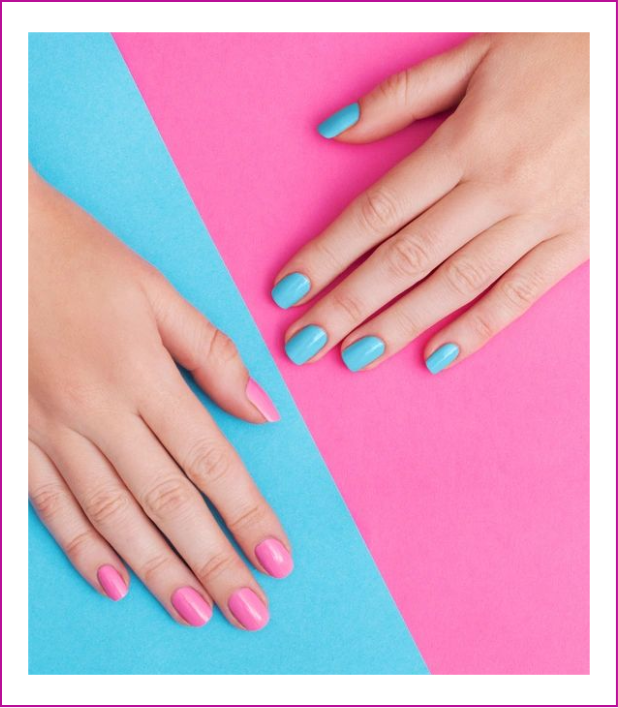 A woman 's hands with blue and pink nail polish on them.